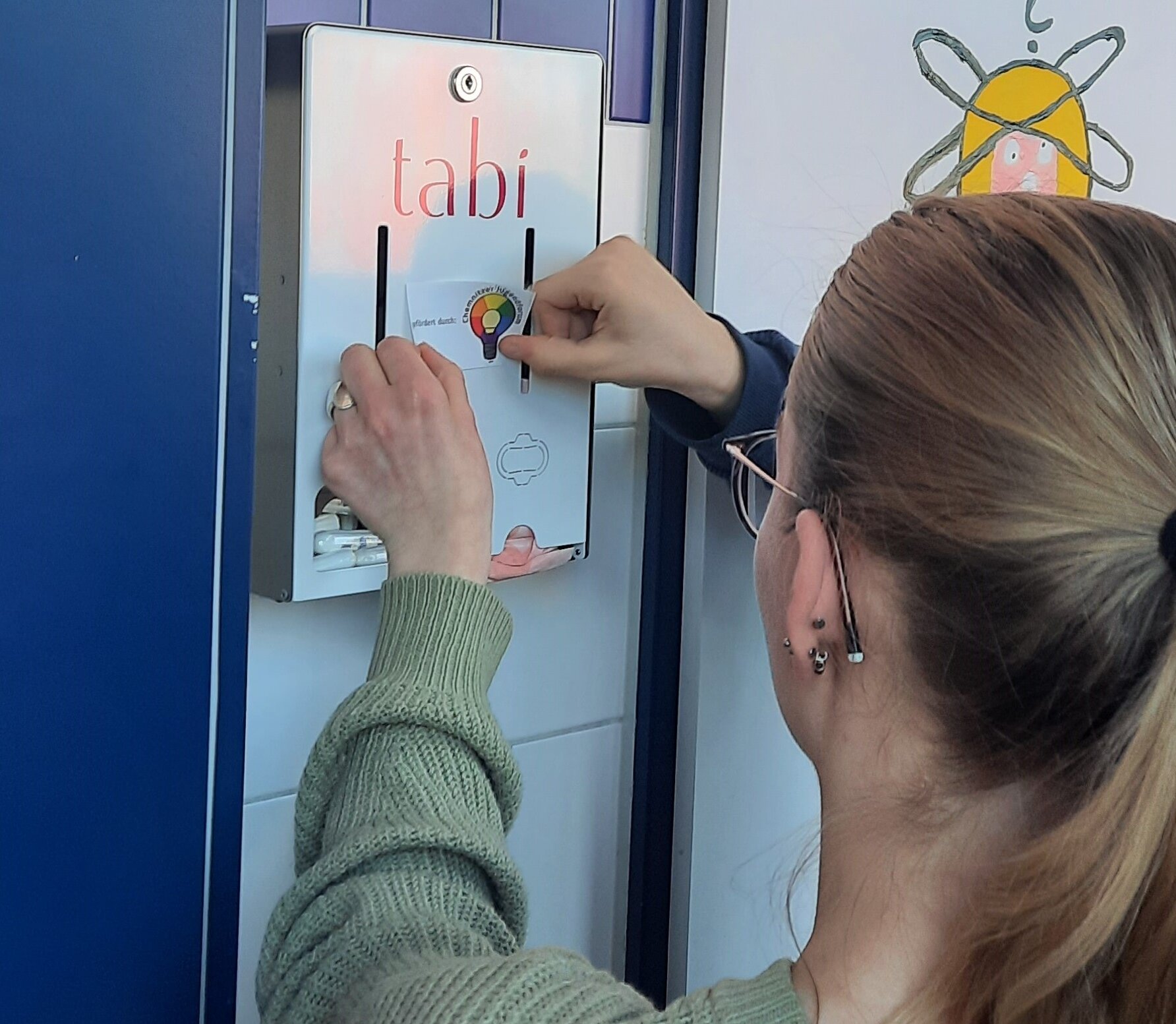 Junge Frau steht vor einem Tabi-Spender